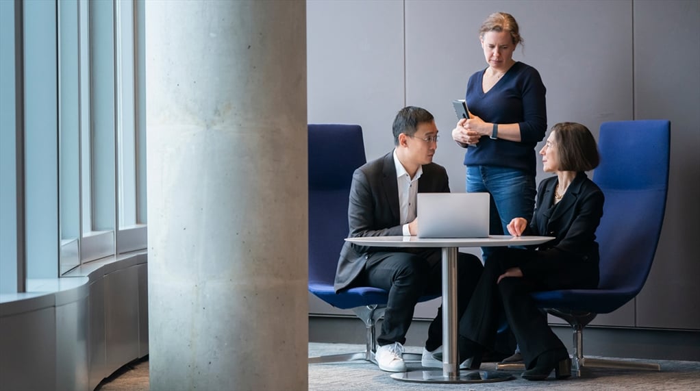 A group pf three people talking around a table